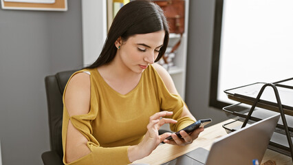 Hispanic woman using smartphone in modern office, exemplifying professionalism and connectivity.