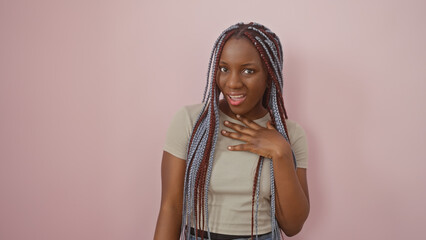 African american woman with braids posing confidently against a pink isolated background,...