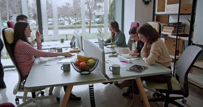 Multicultural business team in a productive office meeting uses a technology to find project solutions, highlighting their collaborative and tech-savvy approach to achieving goals.