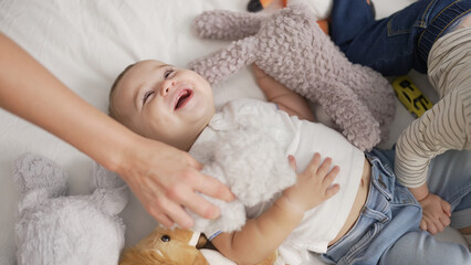 Adorable toddler smiling confident lying on bed with dolls at bedroom