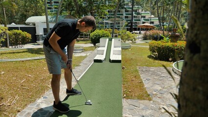 Man playing mini golf on green course during leisure activity at resort. Enjoyable sports and...