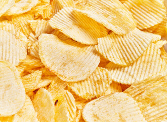 Close-up view of crispy, salty potato chips texture, implying a concept of snack, junk food, or...