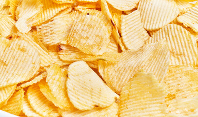 Close-up of golden crispy potato chips with ridges, filling the frame.