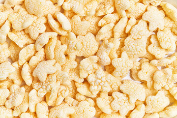 Close-up of yellow rice crackers against a white background with ample texture.