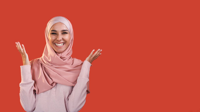Joy expression. Cheerful wow. Unexpected surprise. Amazed excited pleased smiling woman in hijab isolated on red empty space background. - Powered by Adobe