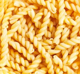 A close-up of uncooked yellow fusilli pasta arranged densely to fill the entire frame.