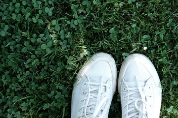 White sneakers against the grass. White sneakers on green background. 