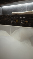 A luxurious bathtub filled with foam under vintage taps and atmospheric lighting.