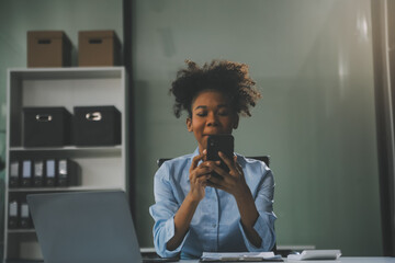 Happy excited successful Asian businesswoman triumphing with a laptop computer smartphone in the...