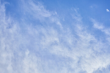 Blue sky scattered with wispy cirrus clouds creating a serene atmospheric background.