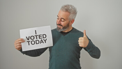 Smiling bearded man holding a sign saying 'i voted today' and giving a thumbs up against a white...