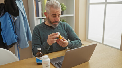 Middle-aged man examines medication during an online consultation in a home office.
