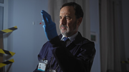 Middle-aged man analyzing evidence at a crime scene in an indoor setting.