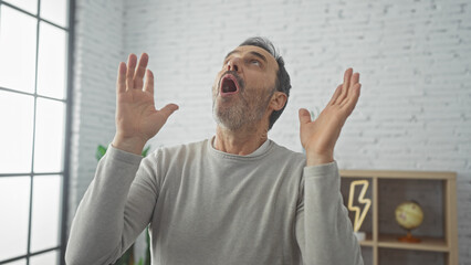 A surprised bearded man raising his hands in a modern living room, emotions, shock, adult, male,...