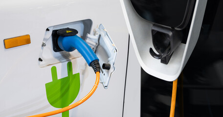 Close up of electric car inlet with a connected charging cable.