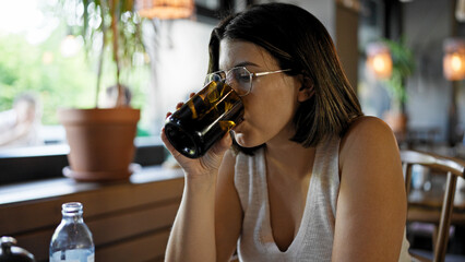 Young beautiful hispanic woman drinking a glass of water at the restaurant