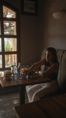 A beautiful hispanic woman dines alone in a modern restaurant with soft ambient lighting and wooden furniture.