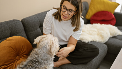 A young woman interacts affectionately with a fluffy dog in the cozy setting of a modern living room.
