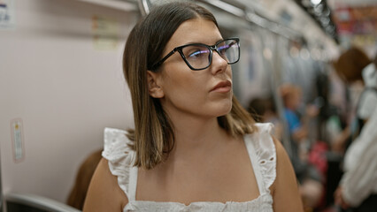 Beautiful hispanic woman with glasses standing, waiting amidst subway transit, urban city's...