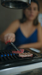 Modern dining experience, young woman's hands cook delicious, rare wagyu beef on grill in japanese restaurant, savoring the juicy roasted meat