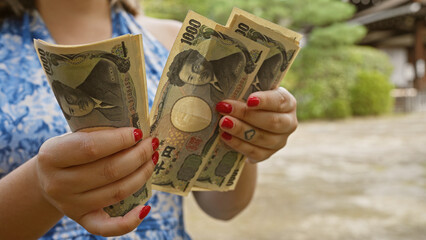 Caucasian young woman's hands counting wealth of japan yen banknotes at traditional heian jingu,...