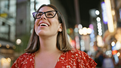 Confident and carefree, a beautiful hispanic woman wearing glasses stands enjoying osaka's famous...