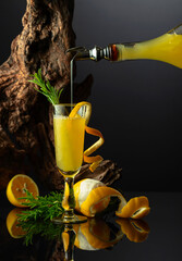 Traditional Italian liqueur Limoncello on a black reflective background.