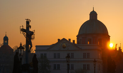 Dawn over the Charles Bridge in Prague and a statue of Jesus Christ with the inscription in Hebrew...