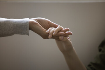 Woman and teenager girl holding hands close up cropped shot. Adult person, psychotherapist, mother...
