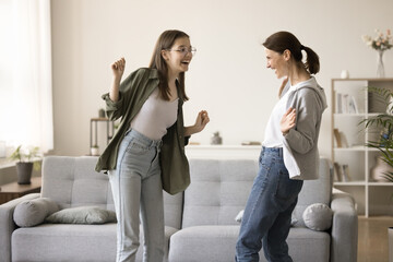 Cheerful dancer mom and teenager daughter kid and dancing at home room, laughing, singing, having...