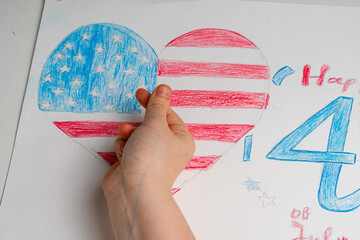 A child's hand shows a heart against the background of his drawing of the American flag in the form...