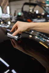 man wearing black gloves applying ceramic coating to car using sponge. Professional car detailing