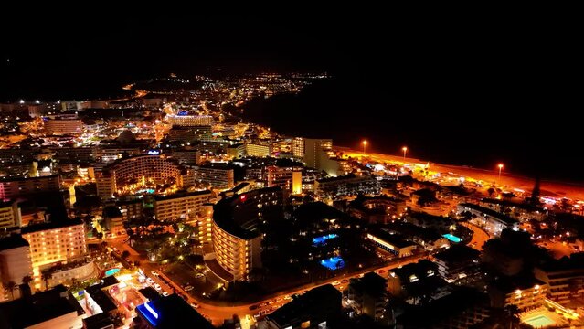 A short night-time drone video captures the lights of Maspalomas, Spain. The city glows like a gem, with bustling streets and bright lights creating a magical atmosphere under the starry sky.