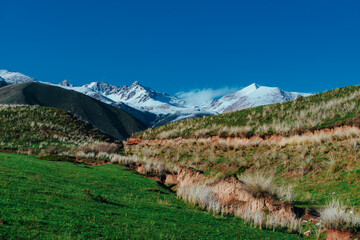 Picturesque mountain valley with snow peaks in spring