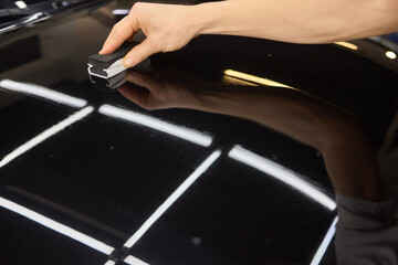 Obraz premium Hand gestures polishing black car hood with sponge
