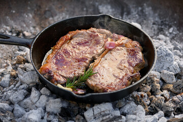 Beef Sirloin steak fried in a cast iron frying pan over charcoal