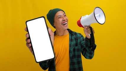 Excited Asian man shows a phone with an empty blank screen for copy space while holding a megaphone...