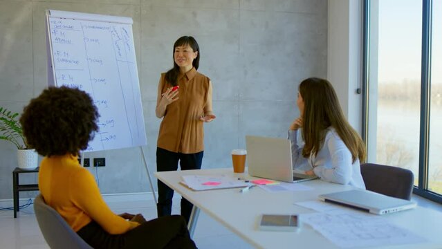 4k video footage of a young businesswoman using a digital tablet while giving a presentation to her colleagues in an office. Young businesswoman doing a presentation in the office.