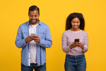 African American man and woman are attentively looking at a cell phone screen. They are standing close together, both focused on the device