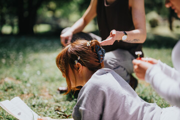 A serene moment captured where young friends relax in a park, one decorating another's hair with...