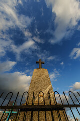 sillhoette of stone grave cross against the background of a blue evening sky with clouds