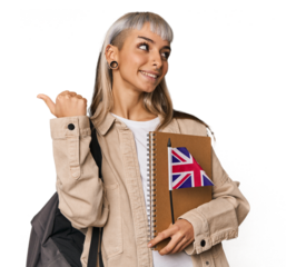 Young erasmus student with books points with thumb finger away, laughing and carefree.