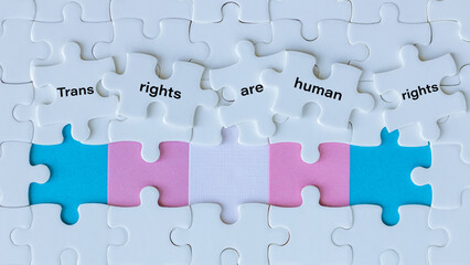 Transgender symbol and words written on white puzzle pieces trans rights are human rights, concept, gender identity and minority rights, copy space