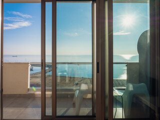 Mediterranean sea maritime scenic view from the half-open panoramic sliding floor-to-ceiling French window over the beach and port in Larnaca, Cyprus, on a warm sunny autumn day.