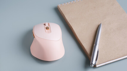 Unusual pink wireless computer mouse with additional buttons and a thumb rest on a blue-green...