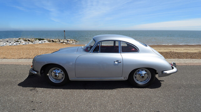 Classic Porsche 356 Coupe automobile parked on seafront  promenade with beach and sea in background.