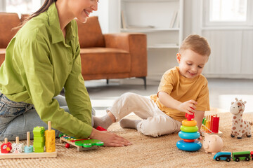 A woman is sitting on the floor playing with a child. The child is smiling and engaging with the...