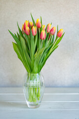 Isolated bouquet of pink and yellow tulips in a crystal vase