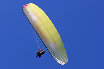 Tandem Paraglider flying in a blue sky	
