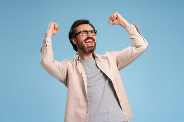 Naklejka premium Excited bearded man gesturing happiness isolated on blue background